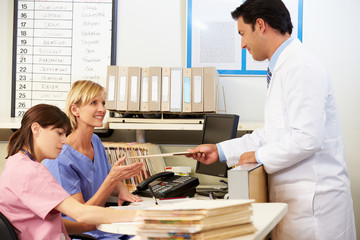 Doctor With Two Nurses Working At Nurses Station