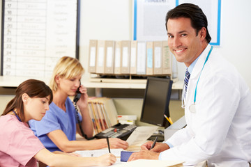 Doctor With Two Nurses Working At Nurses Station