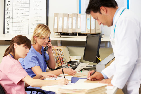 Doctor With Two Nurses Working At Nurses Station