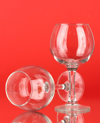 Two empty wine glasses on color background