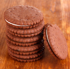 Chocolate cookies with creamy layer on wooden table close-up