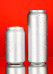 Aluminum cans with water drops on color background