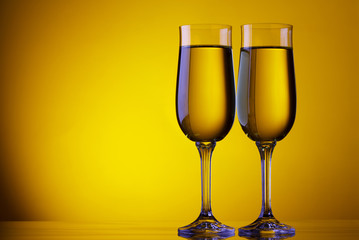 Two champagne flute glasses on yellow background with copy space