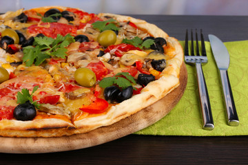 Delicious pizza close-up on wooden table on room background