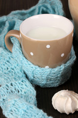 Pitcher and cup of milk with meringues on wooden table close-up