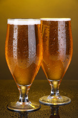 Glasses of beer on yellow background