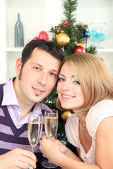 Young happy couple holding glasses with champagne at table near