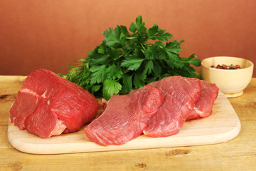 Raw beef meat with spices on wooden table on brown background