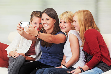 4 girls with smartphones on the sofa