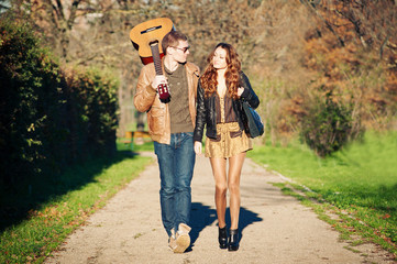Young couple walking in a romantic mood with guitar outdoors in