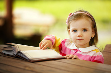 little girl reads a book