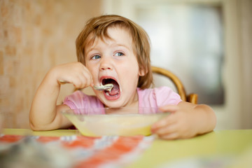 child eats with spoon in home