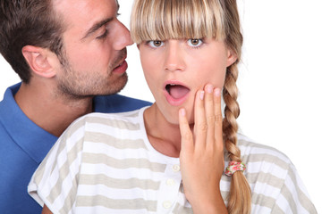 man telling a secret to a woman