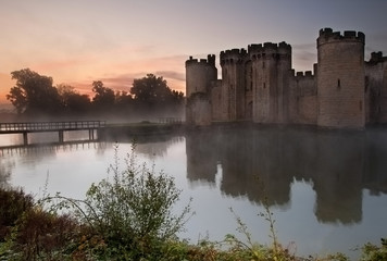 Stunning moat and castle in Autumn Fall sunrise with mist over m