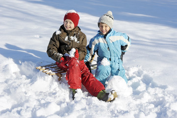 Kinder fahren Schlitten im Schnee