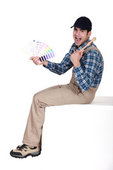 Painter sat with paint brush and swatch