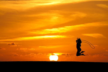 silhouetted girl rope skipping in sunset