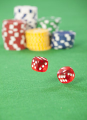 Rolling red dice on a casino table with chips 