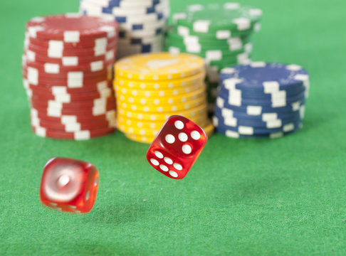 Rolling red dice on a casino table with chips 