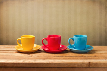 Three colorful coffee cups over vintage background