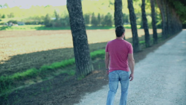 Young man walking in the park, crane shot, slow motion