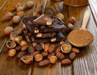 Chocolate with hazelnuts and cocoa beans on a brown table