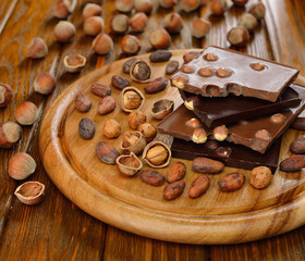 Chocolate with hazelnuts and cocoa beans on a brown table