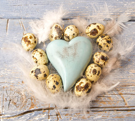 Frohe Ostern: Zarte Dekoration mit blauem Herz, Eiern und Federn