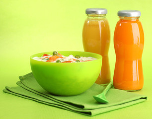 tasty  dieting food and bottles of juice, on green background