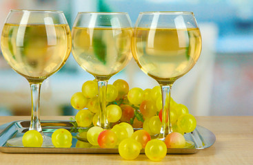 White wine in glass on salver on room background