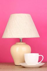 Fototapeta na wymiar lampa stołowa i filiżanki na różowym tle