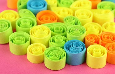Colorful quilling on pink background close-up