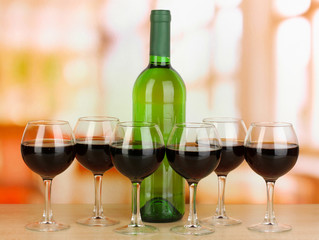 Red wine in glass and bottle on room background