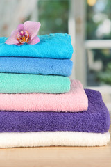 Stack of towels with fragrant flower on window background