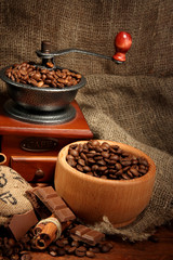 Coffee grinder and cup of coffee on burlap background
