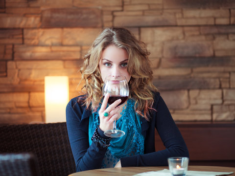 Beautiful Girl In Restaurant holding glass with red wine