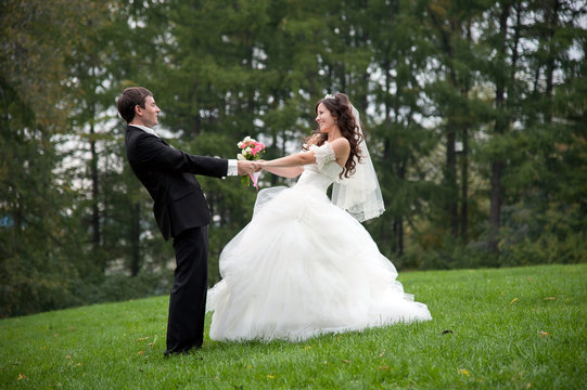 Newly married couple dancing in field