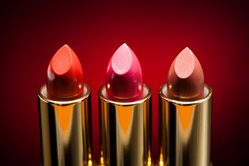 three lipsticks on red background
