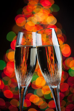 champagne glasses against christmas tree bokeh lights