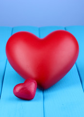 Decorative red hearts on blue wooden table on blue background