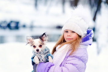 cute little girl with her lovely pets dog chihuahua in winter ou