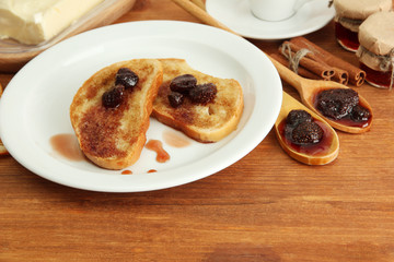 White bread toast with jam and cup of coffee on wooden table