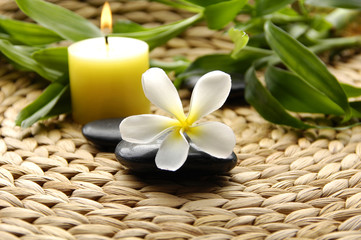 Frangipani and therapy stones on woven bamboo pieces background