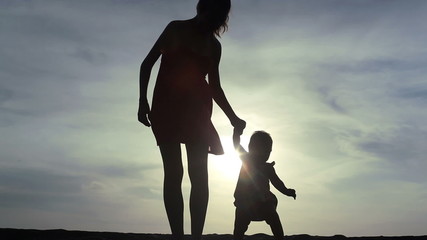 young mother keeping her baby child by the hand