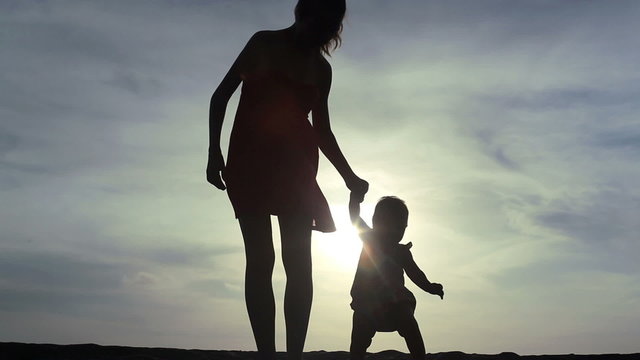 young mother keeping her baby child by the hand