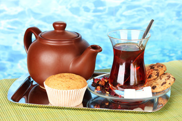 glass of Turkish tea and kettle on color background