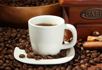 cup of coffee, grinder and coffee beans on brown background