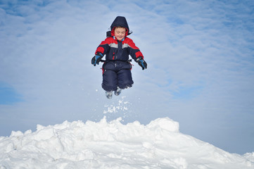 Fototapeta na wymiar Happy little kid is playing in snow
