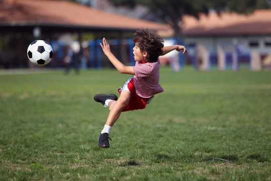 Boy Playing Soccer In The Park