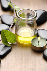 Green leaf and stones and bottle of aromatherapy oil